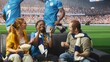 © DC Studio - Football supporters, cheering and celebration as friends on sofa smile, lift fists and react to soccer match. Team pride, shared excitement and matchday joy bring fans together beside stadium pitch.
