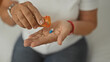 © Krakenimages.com - Middle age hispanic woman pours blue and white capsules from an orange prescription bottle into her bare palm while seated on a bed in a studio; concern recovery.