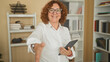 © Krakenimages.com - Woman holding tablet reaches out hand for handshake in a building office with bookshelves and desk, smiling and offering welcome; friendly greeting.