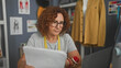 © Krakenimages.com - Woman dressmaker reads pattern paper with hand on chin and tape measure around neck in studio; thoughtful planning.