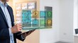 © Majed - Estate agent hands using stylus on tablet with floating glass icons for property listing, price and viewing availability in bright modern agency office