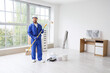 © Pixel-Shot - Home renovation and interior improvement, professional painter holding a roller in a bright empty room during apartment refurbishment and repair work