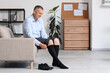 © Pixel-Shot - Compression therapy and venous health, mature man putting on medical compression stockings for circulation support and leg swelling relief in home office
