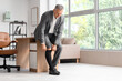© Pixel-Shot - Varicose veins and circulation health, mature businessman putting on compression socks in office to manage leg pain and venous insufficiency symptoms