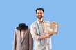 © Pixel-Shot - Fashion design and tailoring, professional tailor holding clothing patterns with mannequin in studio on blue background