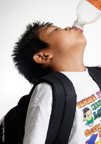 boy wearing a knapsack taking a drink