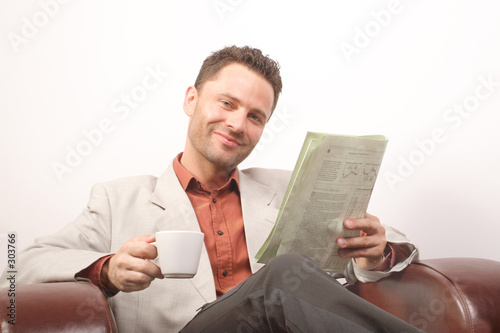 smiling handsome man with newspaper and cup of cof photo