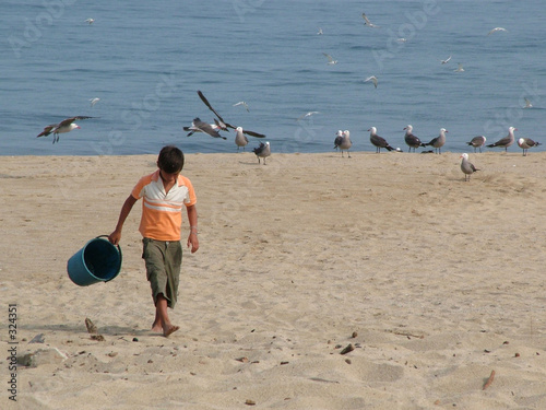 garcon avec les oiseaux sur la plage photo