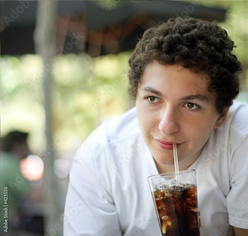 Teenage boy drinking cola soda outdoors photo