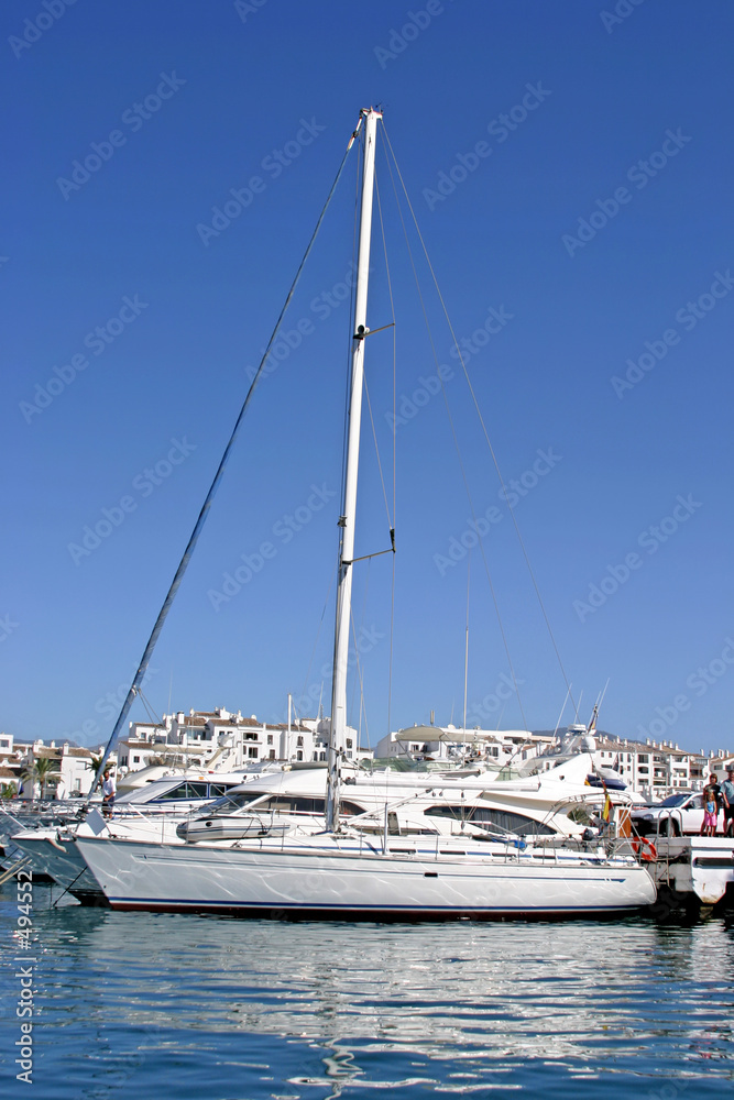 yacht and reflection of blue sky in blue water of harbour or por