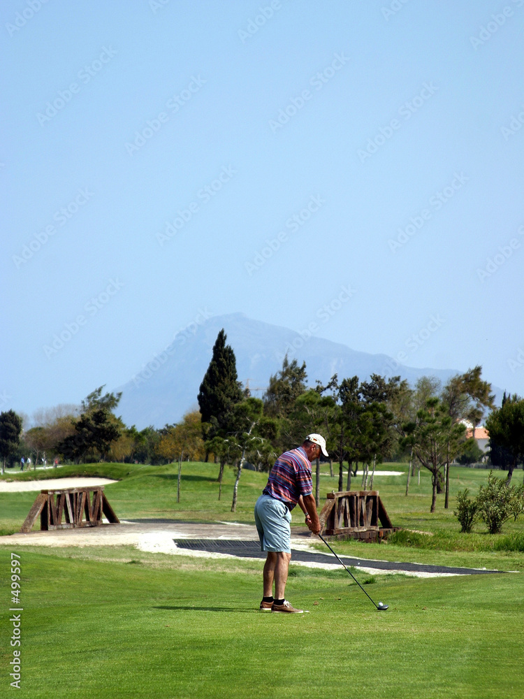 Obraz premium man teeing off on pretty golf course in sunny spain
