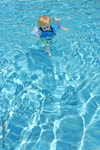 young boy learning to swim in pool