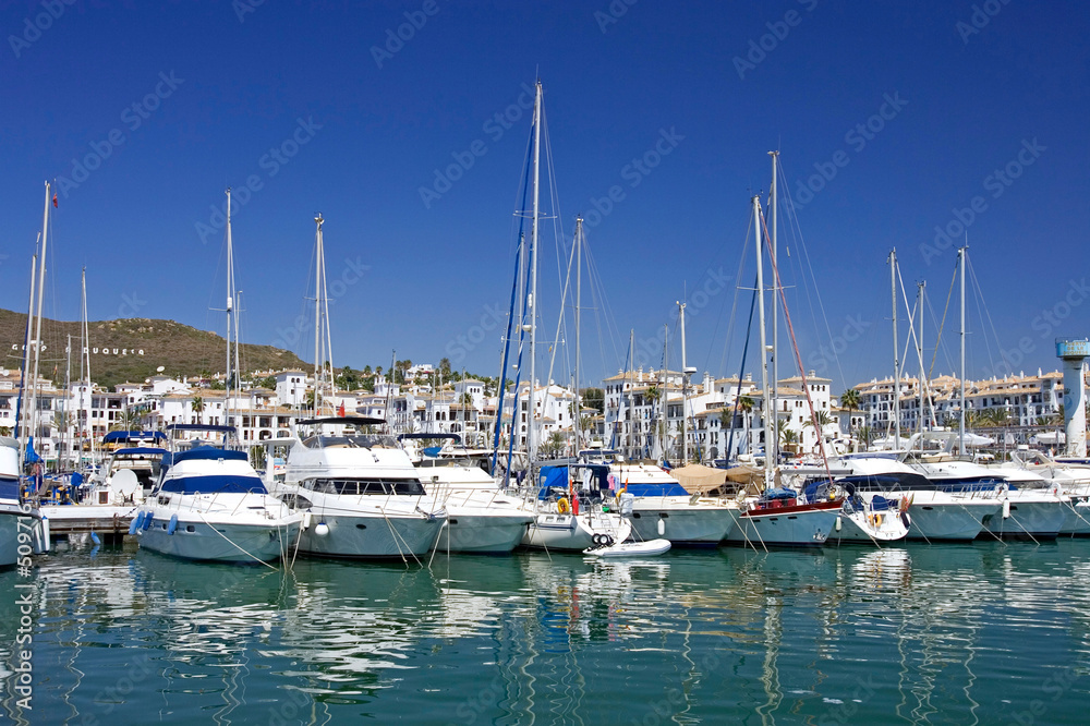 tall luxury boats and yachts moored in duquesa port in spain on
