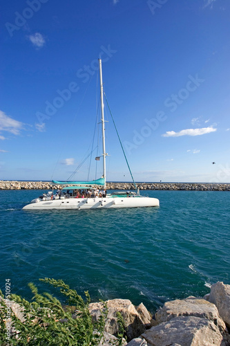 large, luxury white catamaran leaving puerto banus harbour