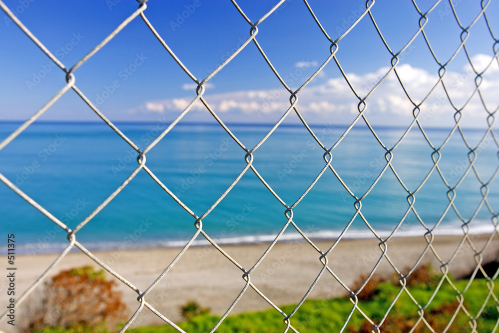 beautiful paradise beach seen through wires of a fence beautiful paradise beach seen through wires of a fence