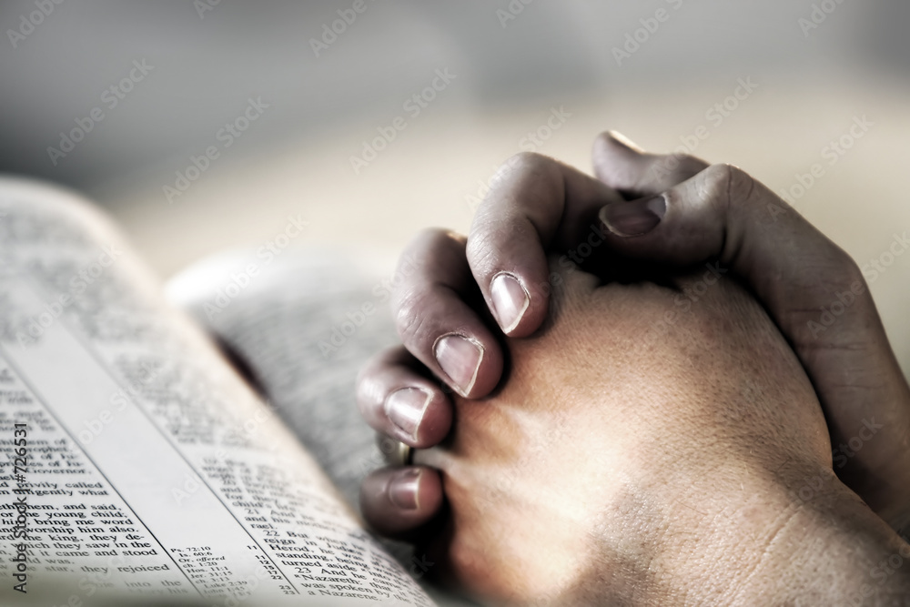 praying hands over a holy bible - obrazy, fototapety, plakaty 