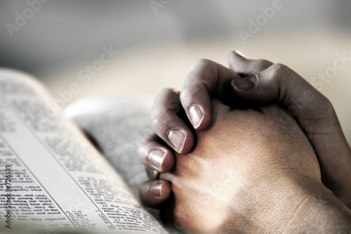 Fotografiet praying hands over a holy bible