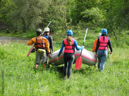 rafting team carrying the boat on the river-bank
