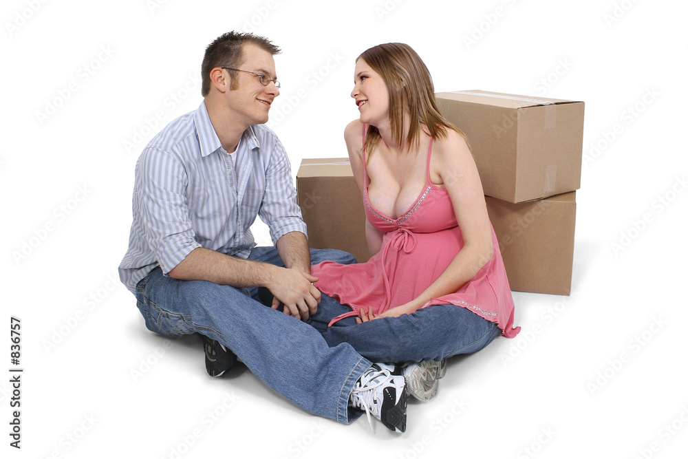 expecting couple sitting near moving boxes expecting couple sitting near moving boxes