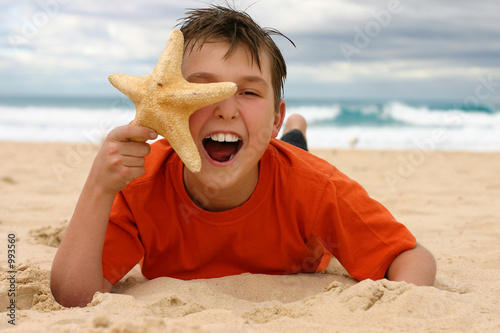 laughing boy with starfish on the beach