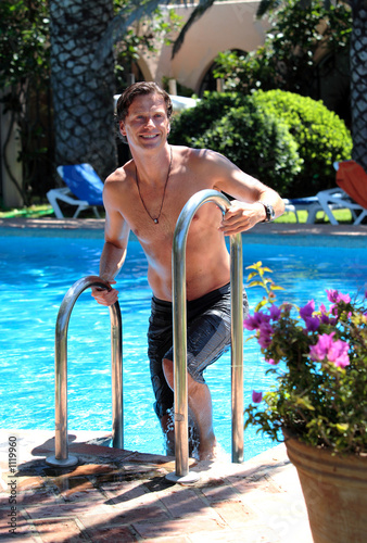 handsome middle aged man climbing out of swimming pool