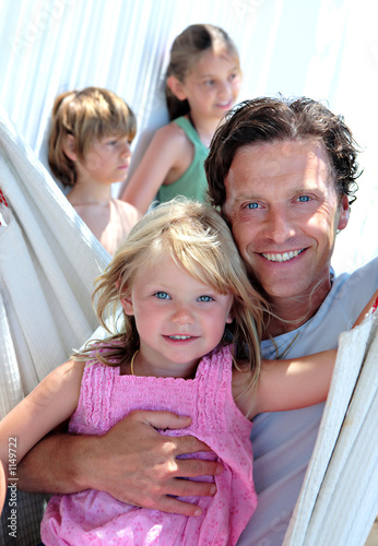 young father and children sitting in a hammock on vacation