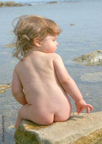 enfant  nu assis au bord de l'eau