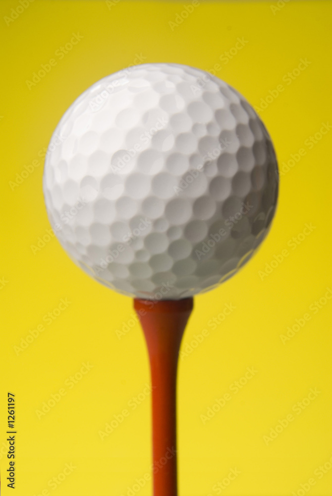 golf ball on red tee, yellow background golf ball on red tee, yellow background
