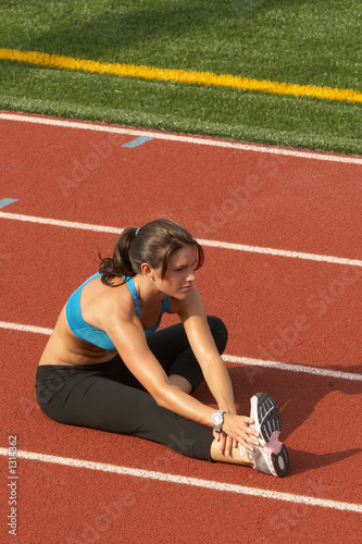 young woman in sports bra stretching hamstring