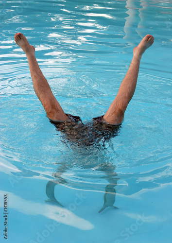 man does a handstand in a swimming pool