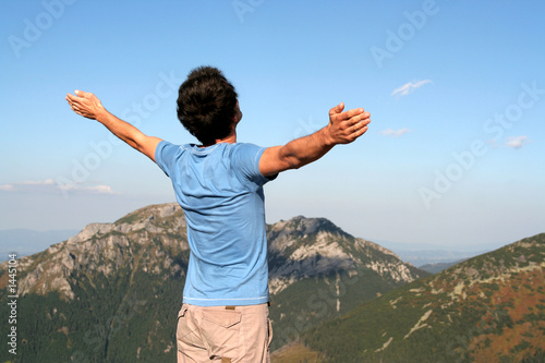 man with arms outstretched in mountains