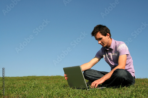 young man using a laptop outdoors © pikselstock