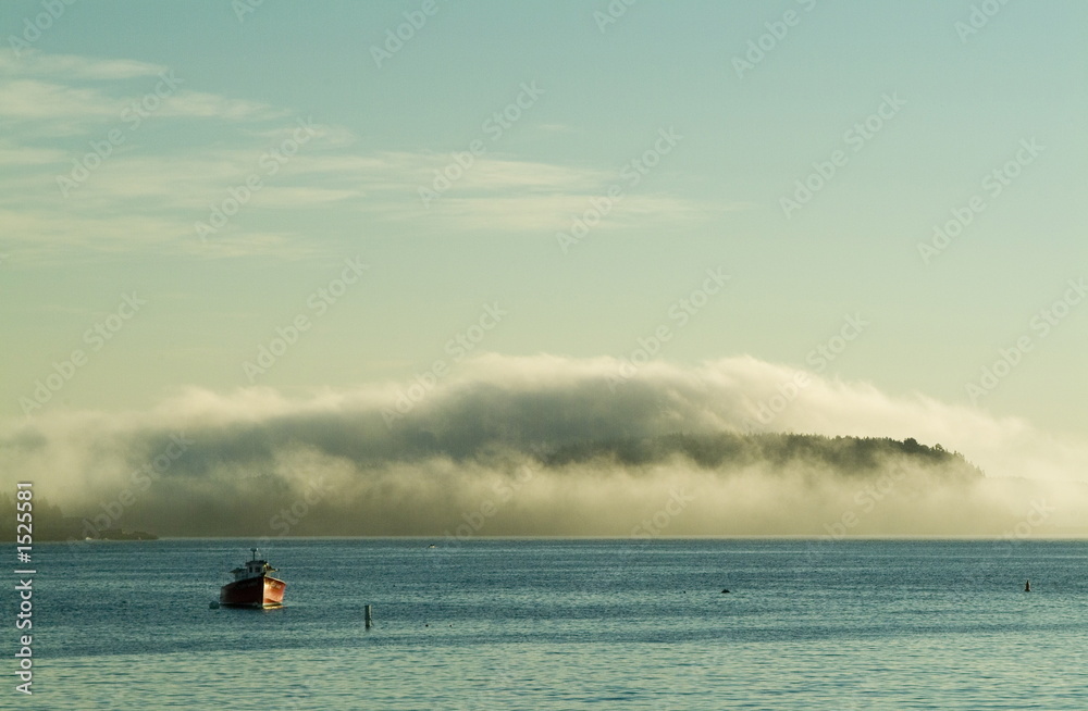 island covered by fog and lobster boat
