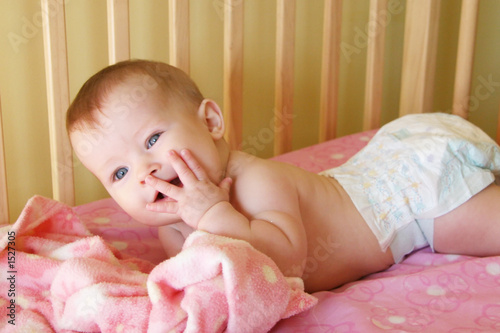 baby girl in crib with hand to face