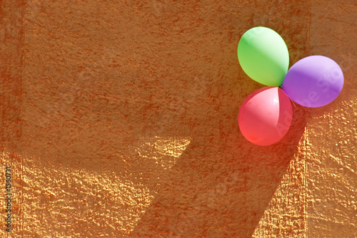 three colorful party balloons and orange textured wall photo