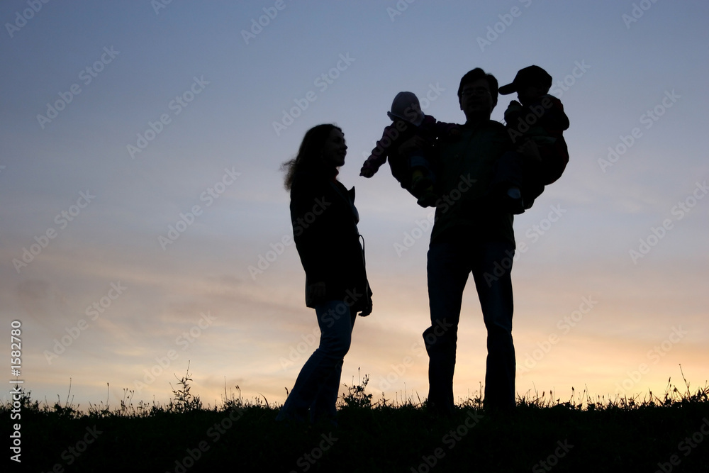 family with children on hands, sunset sky