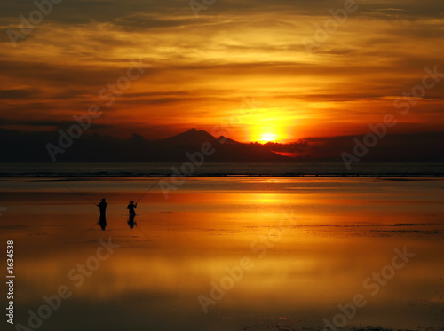 fishing at dawn under an incredible orange sunrise, bali.