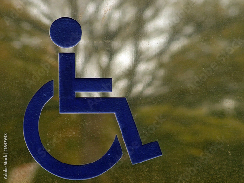 metal disabled sign reflecting a tree