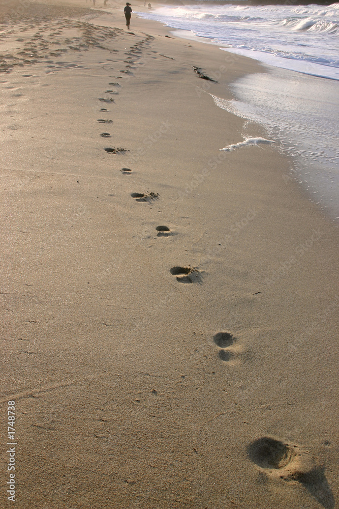 footprints and a woman in the distance jogging alo footprints and a woman in the distance jogging alo