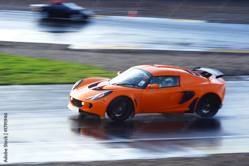 Fototapeta premium orange sports car on wet race circuit