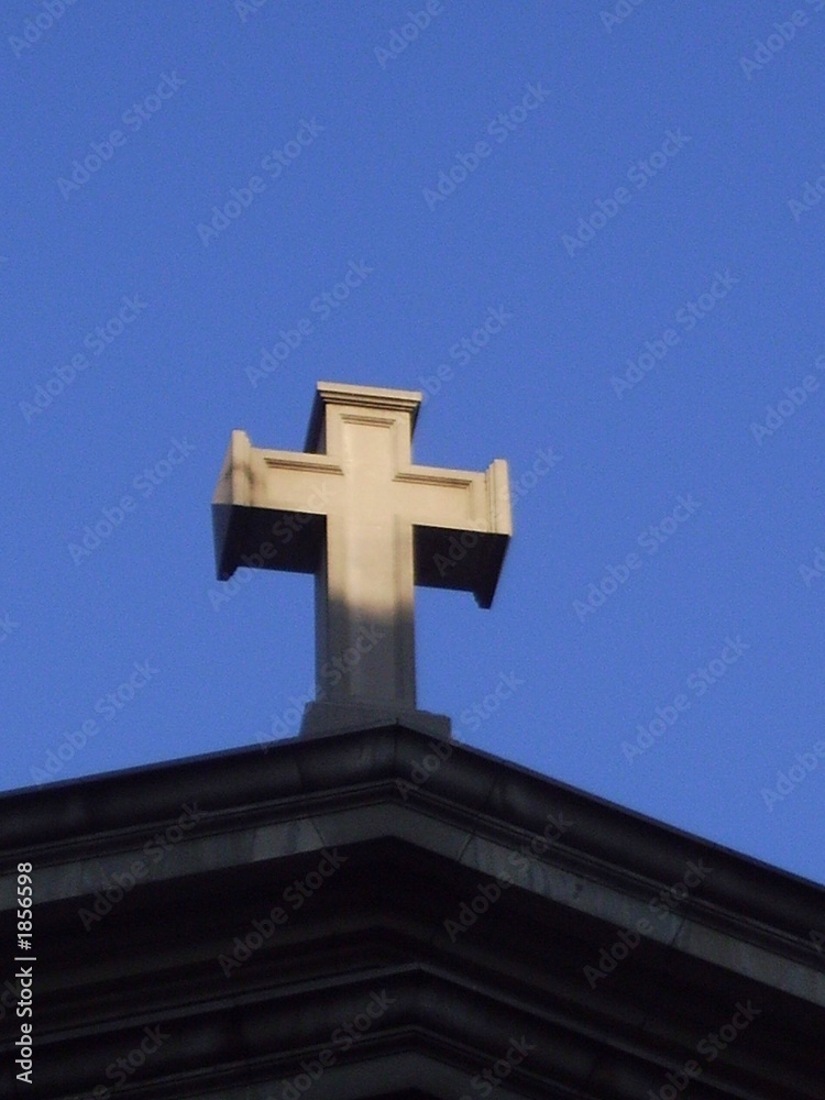 stone cross on church against blue sky