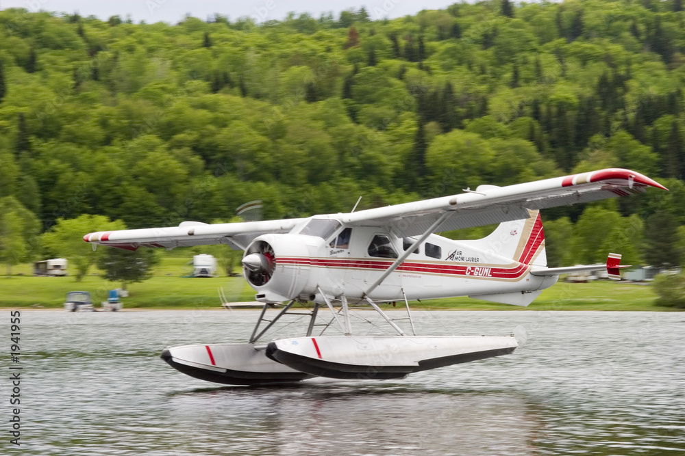 Naklejka premium float plane landing on a calm lake's water in the Canadian province of Quebec