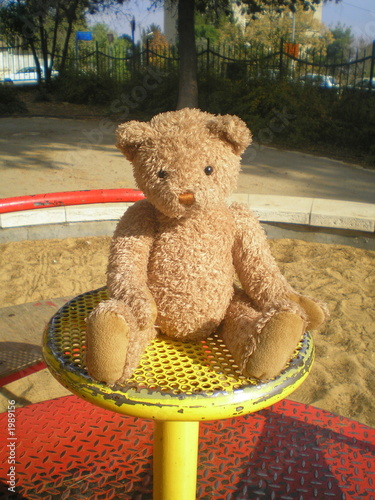 teddy bear on the merry-go-round on the payground photo