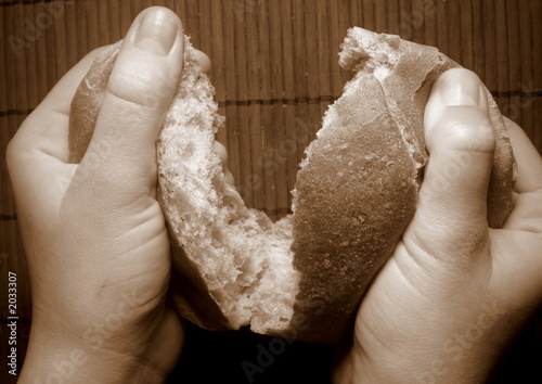 hands breaking the fresh roll of dark bread