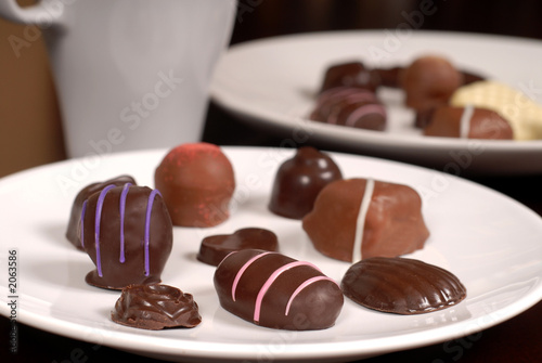 close up of two plates of chocolates with a cup of hot chocolate