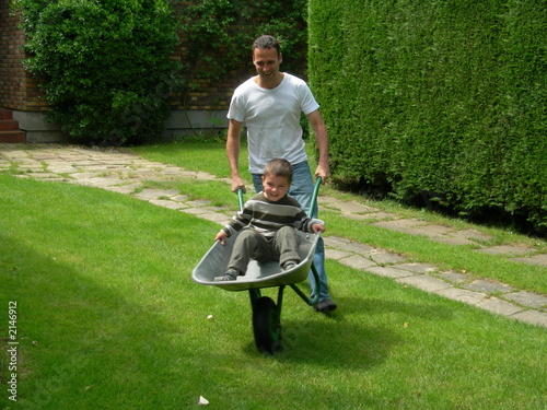 père poussant son fils dans une brouette photo