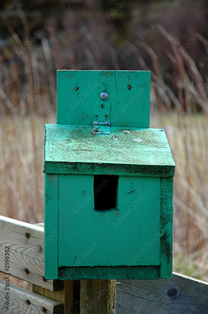 Wooden green bird box on a wooden fence with grass and straw in the background. Wooden green bird box on a wooden fence with grass and straw in the background.