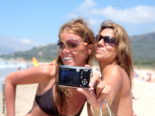 two pretty young girlfriends taking a photo of the