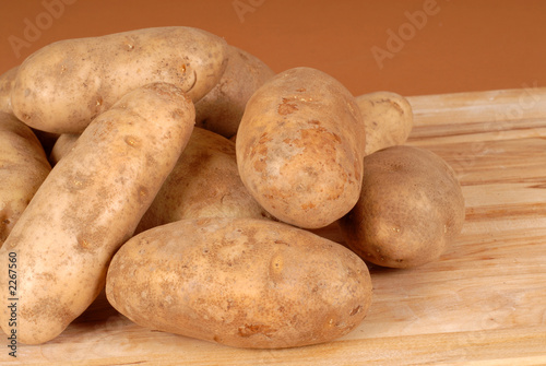 Φωτογραφία several russet potatoes piled on a cutting board