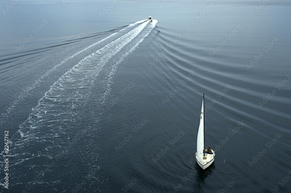 Fototapeta premium One sail boat and one yacht heading in different direction. Beautiful ripples in the water.